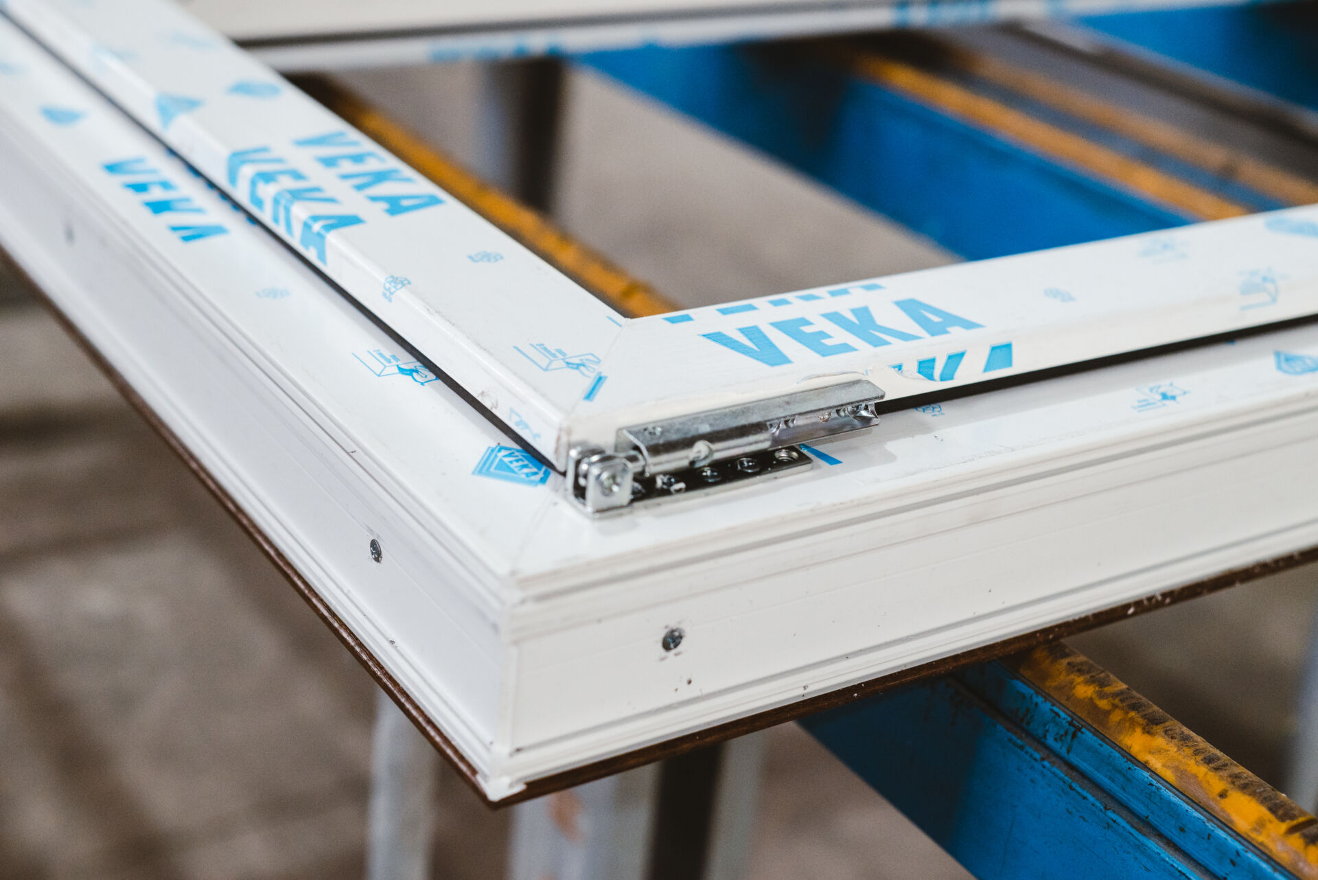 Angolo di telaio in PVC bianco con pellicola protettiva azzurra VEKA e cerniera metallica, prodotto da D'Arcangelo